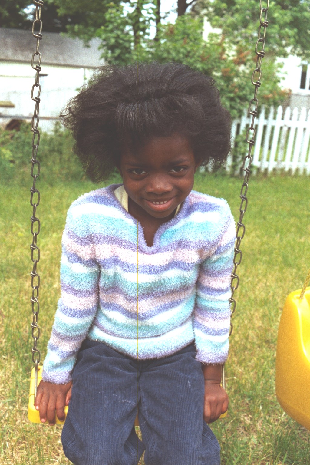 Blessin, with her hair prepared for her aunt Kim's wedding, sits on her swing in the back yard.
