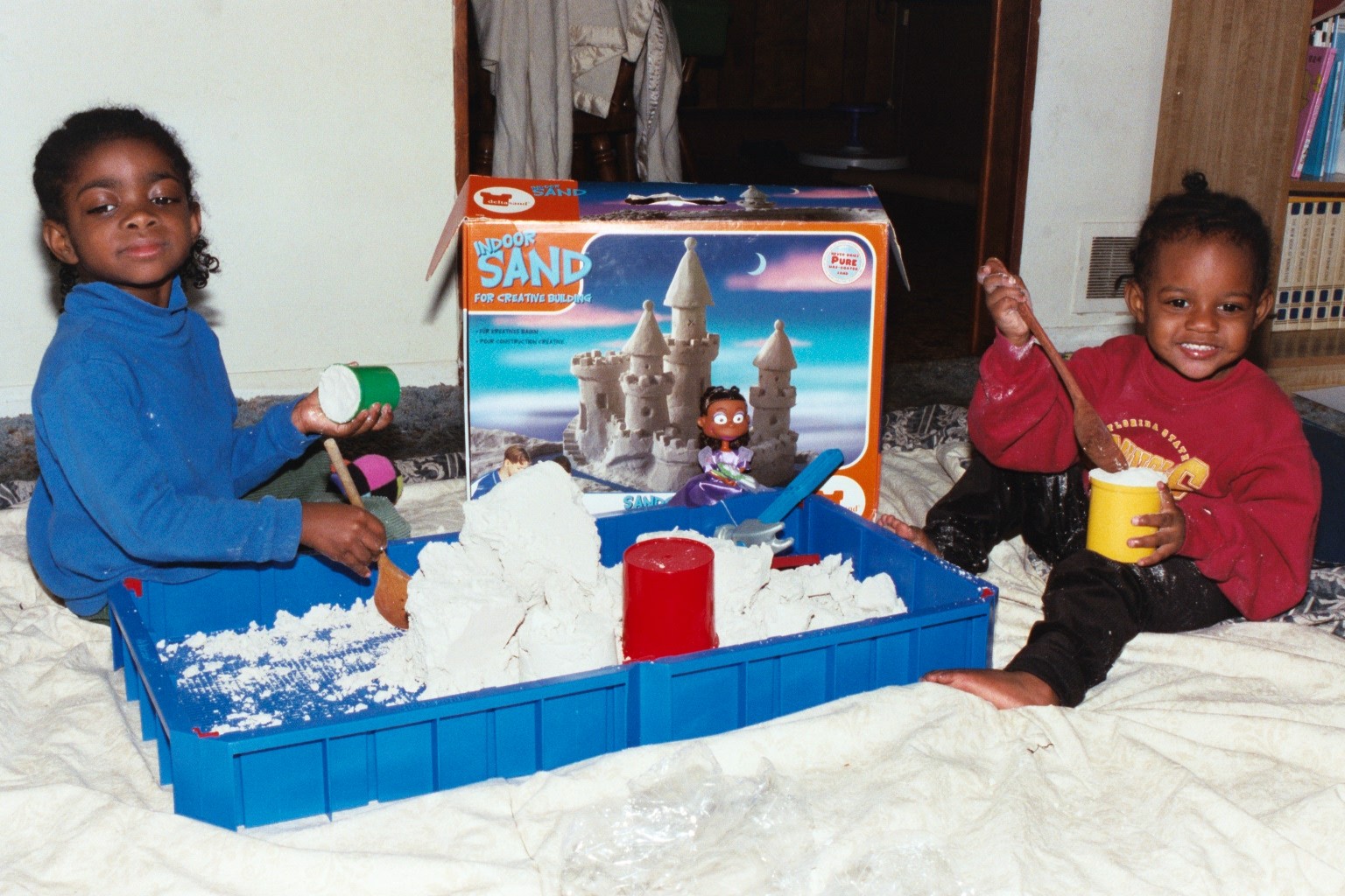 Fortune and Blessin play in indoor sand.